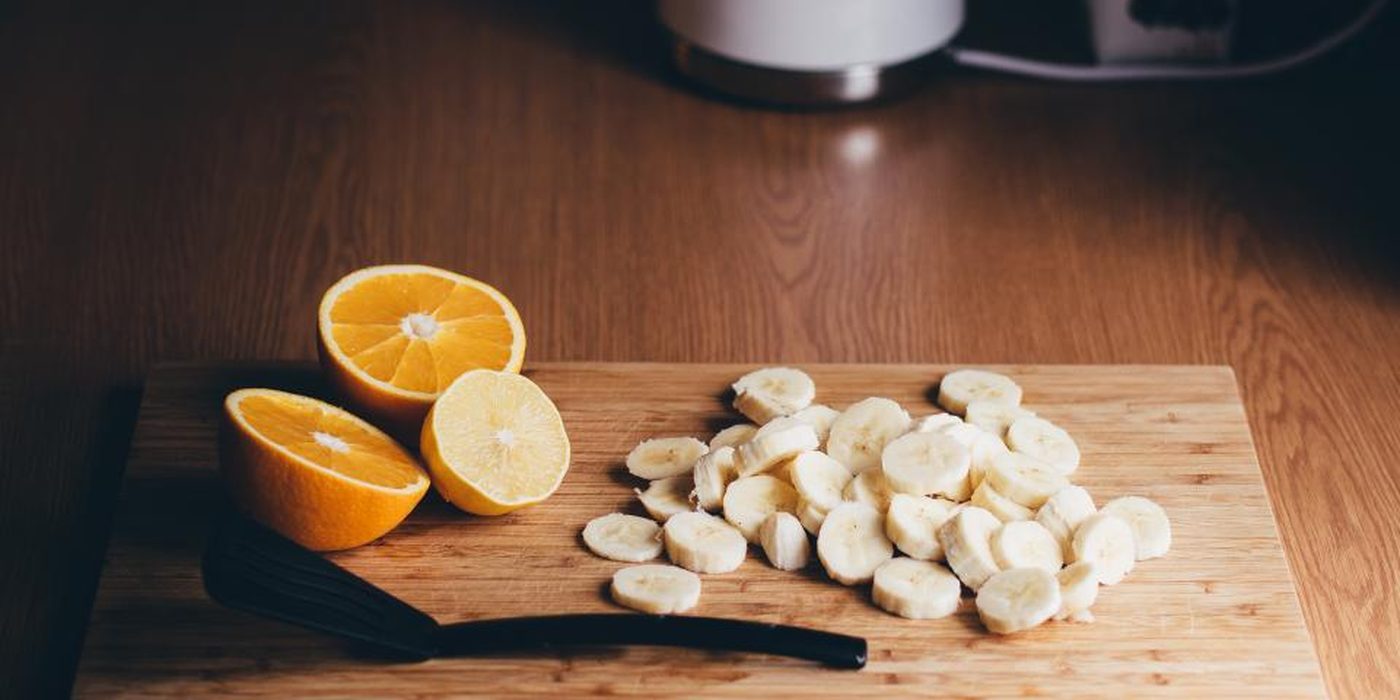Halved oranges and sliced banana on a wooden chopping board.