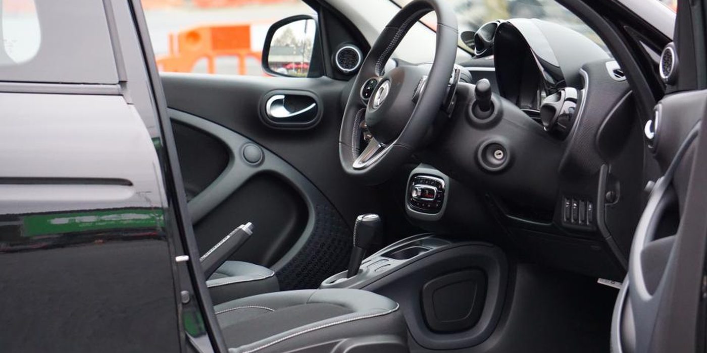 An open car door showing the driver's seat, steering wheel and centre console.