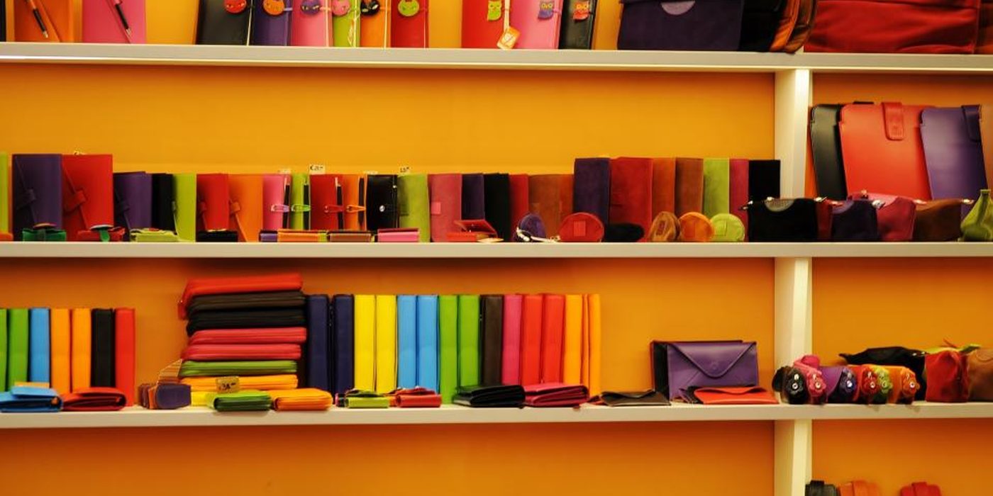 A retail shelf displaying wallets and notebooks arranged in blocks of colour.