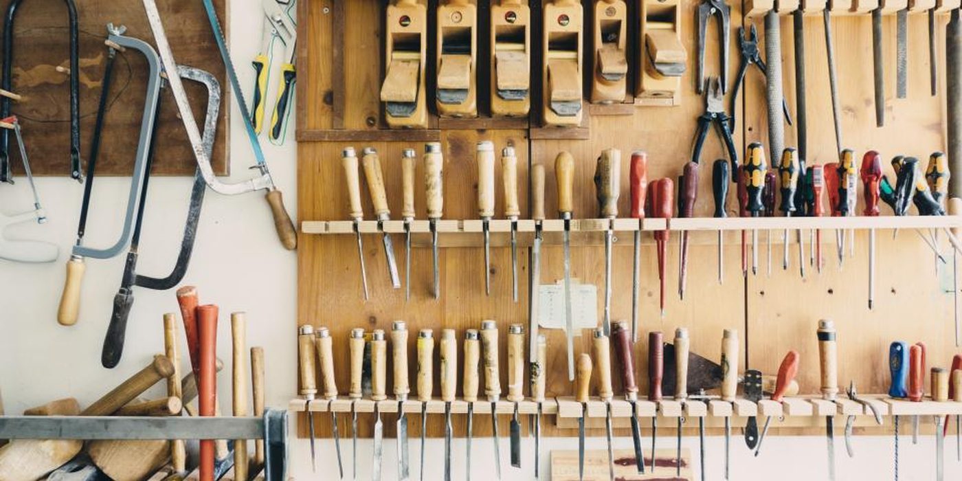 A workshop pegboard hung with saws, chisels, pliers and screwdrivers in ordered rows.