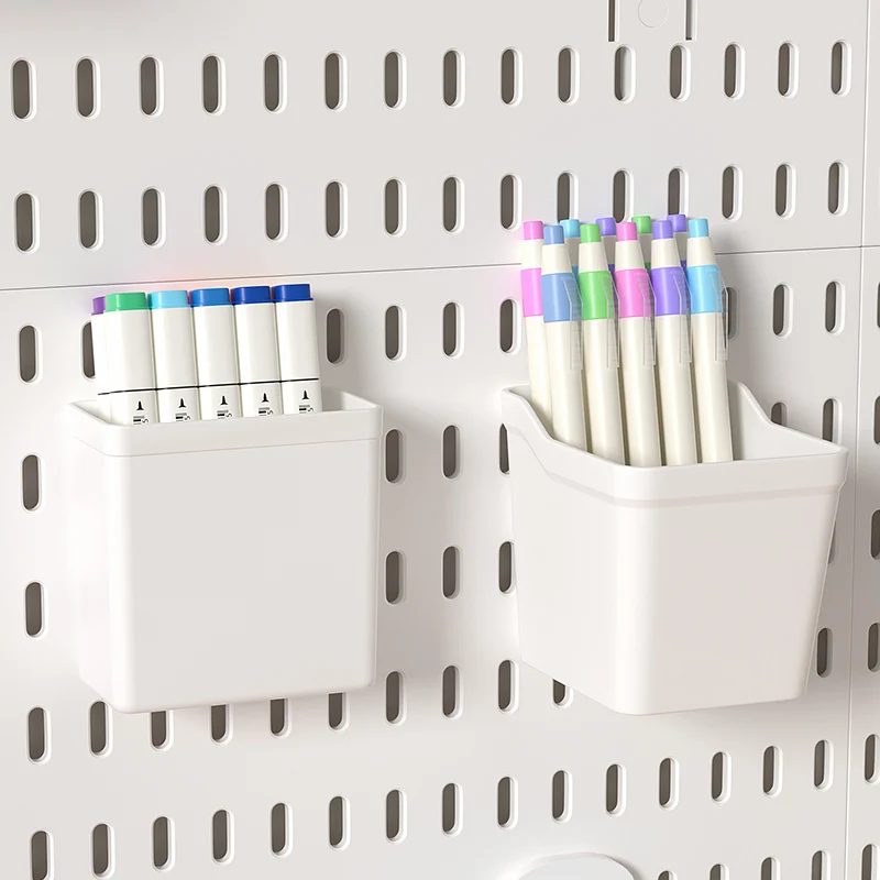 Two white pegboard cups clipped to a white slotted panel, one holding marker pens and the other holding fineliners