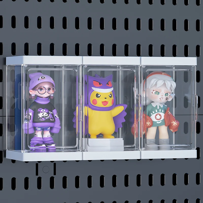 Three clear display boxes holding collectible figurines, mounted in a row on a dark grey slotted pegboard wall