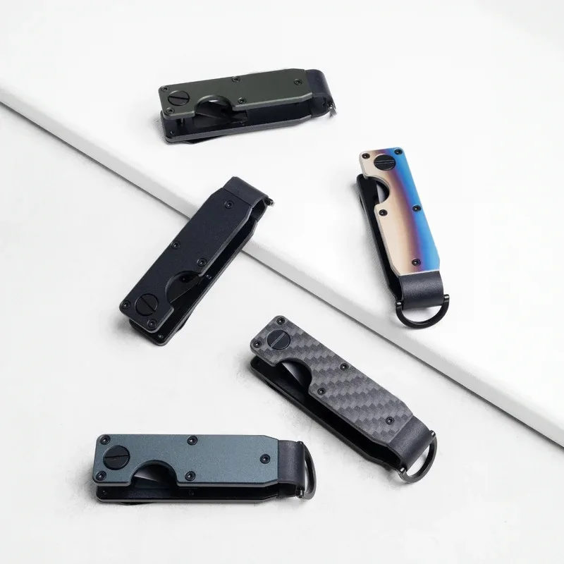 Five folding key organizers closed on a white surface in olive, black, iridescent, carbon fibre and slate blue