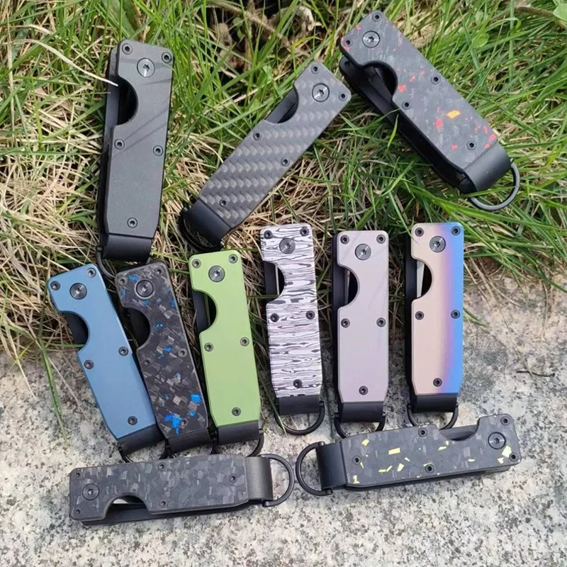 Folding key organizers laid out on grass in carbon fibre, marbled, green, blue and iridescent finishes