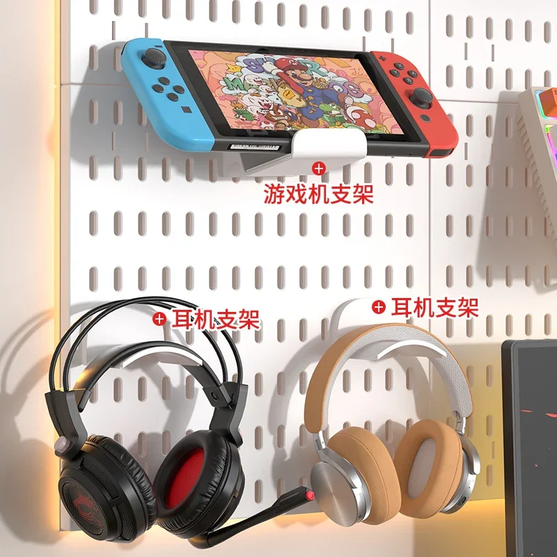 Nintendo Switch console resting in a white pegboard holder above two pegboard hooks holding gaming and over-ear headphones