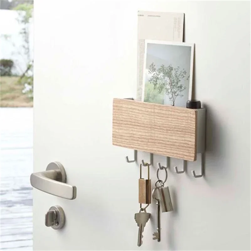 Bamboo-finish key holder on a hallway wall by the door, post and a card in the tray, keys and padlocks hanging beneath