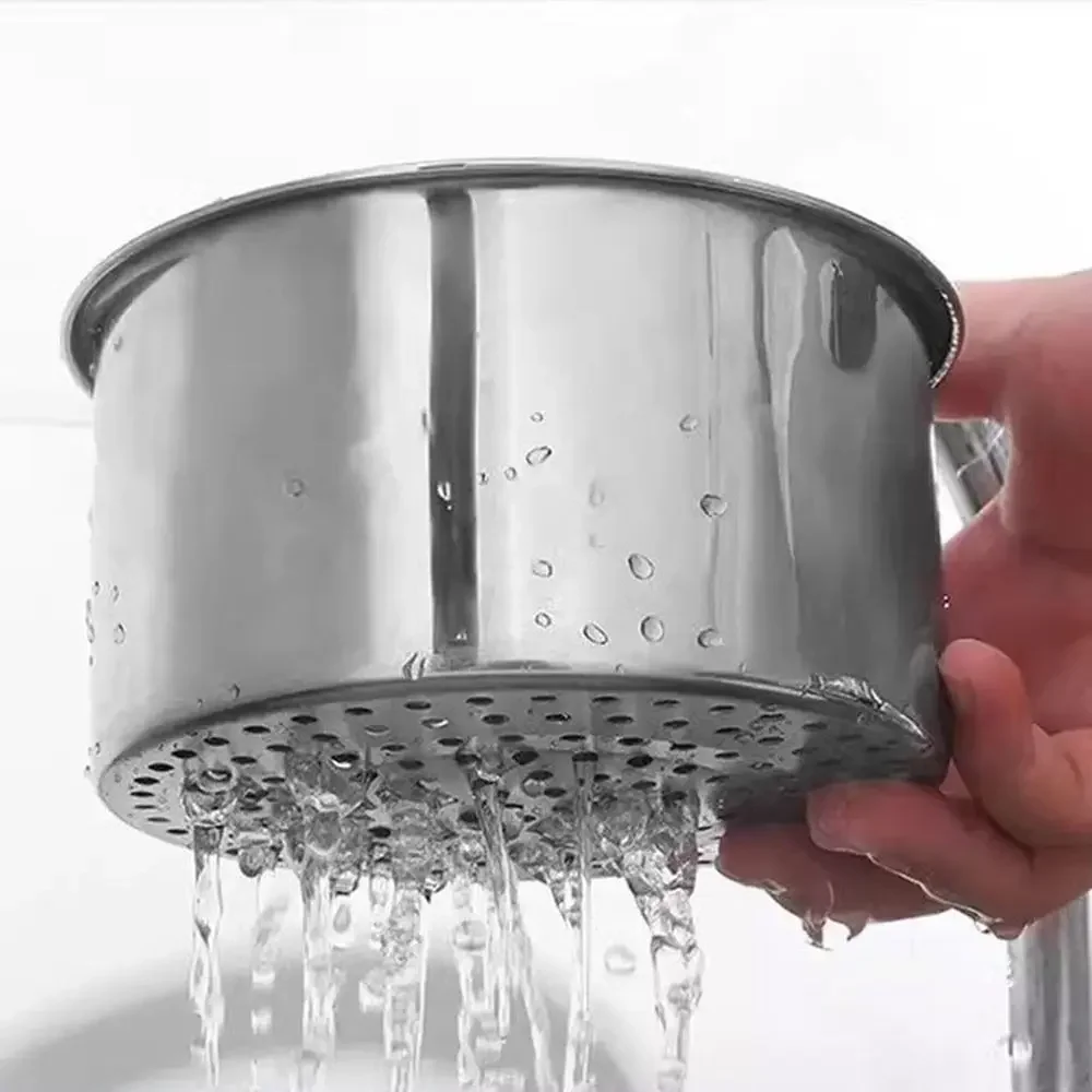 Hand holding the stainless steel strainer basket as water streams out through the punched holes in its base