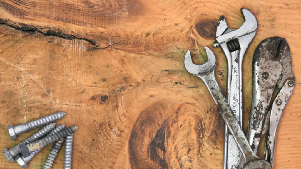 Two adjustable spanners and a scattering of screws on a worn wooden workbench.