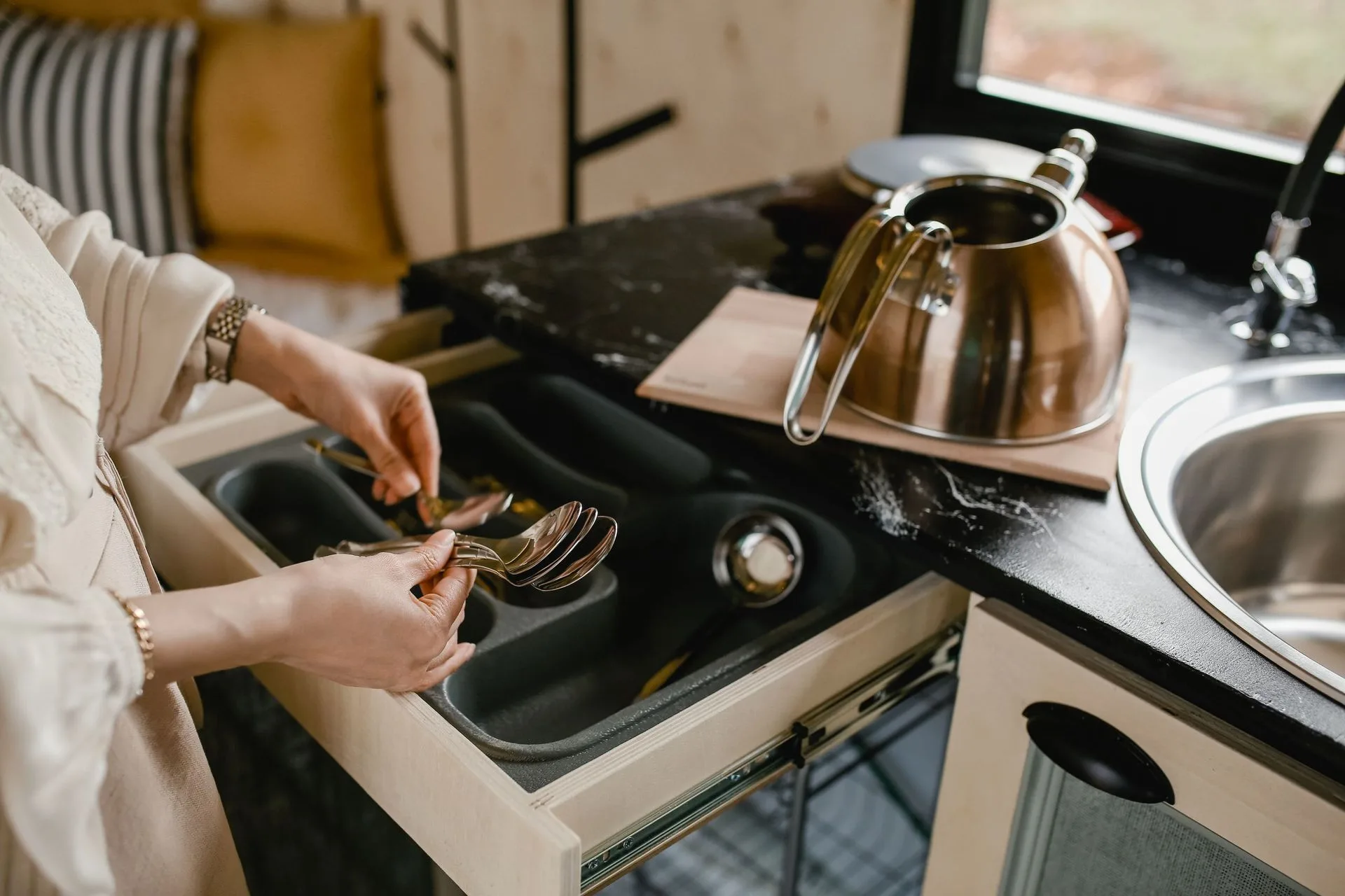 A cluttered kitchen drawer being tidied